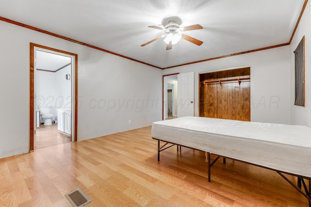 bedroom with crown molding, visible vents, wood finished floors, and ensuite bathroom