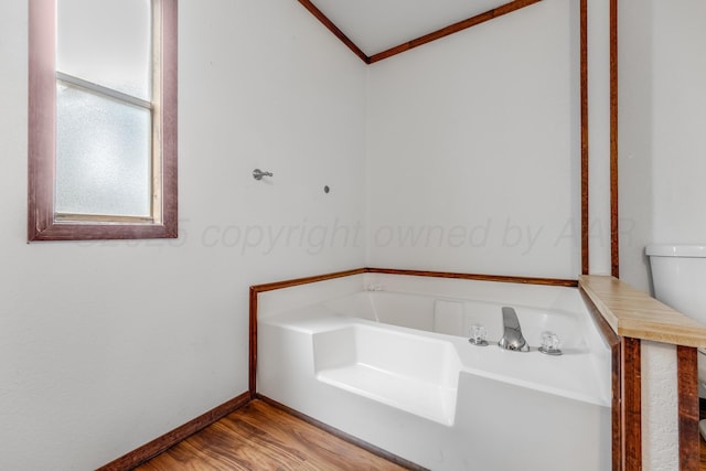 bathroom featuring ornamental molding, a garden tub, baseboards, and wood finished floors