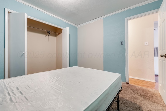 carpeted bedroom with a closet, ornamental molding, and a textured ceiling