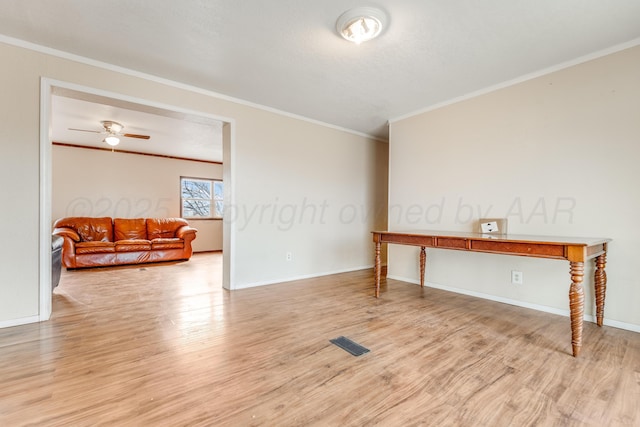 empty room featuring ceiling fan, visible vents, baseboards, light wood-style floors, and crown molding