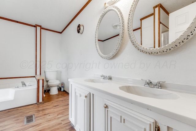 bathroom featuring ornamental molding, visible vents, a sink, and wood finished floors