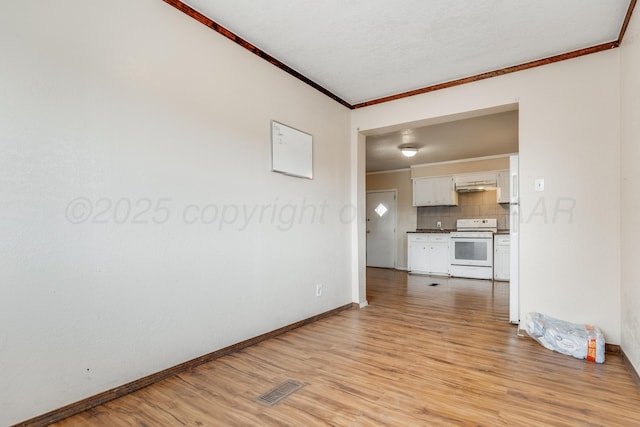 unfurnished living room with ornamental molding, visible vents, light wood-style flooring, and baseboards