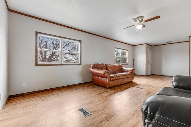 living room with light wood-type flooring, visible vents, and crown molding