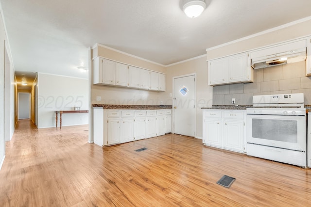 kitchen featuring dark countertops, white cabinets, visible vents, and white gas range