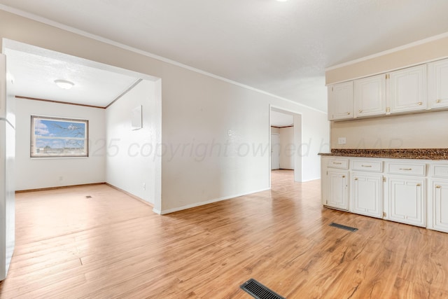 kitchen featuring baseboards, visible vents, white cabinets, crown molding, and light wood-type flooring