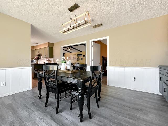 1620 Takewell St, Borger, TX 79007 - dining space with wainscoting, wood finished floors, a textured ceiling, and a decorative wall