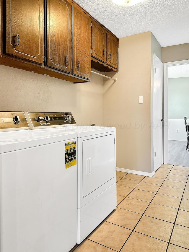 1620 Takewell St, Borger, TX 79007 - laundry area featuring independent washer and dryer, cabinet space, light tile patterned floors, a textured ceiling, and baseboards