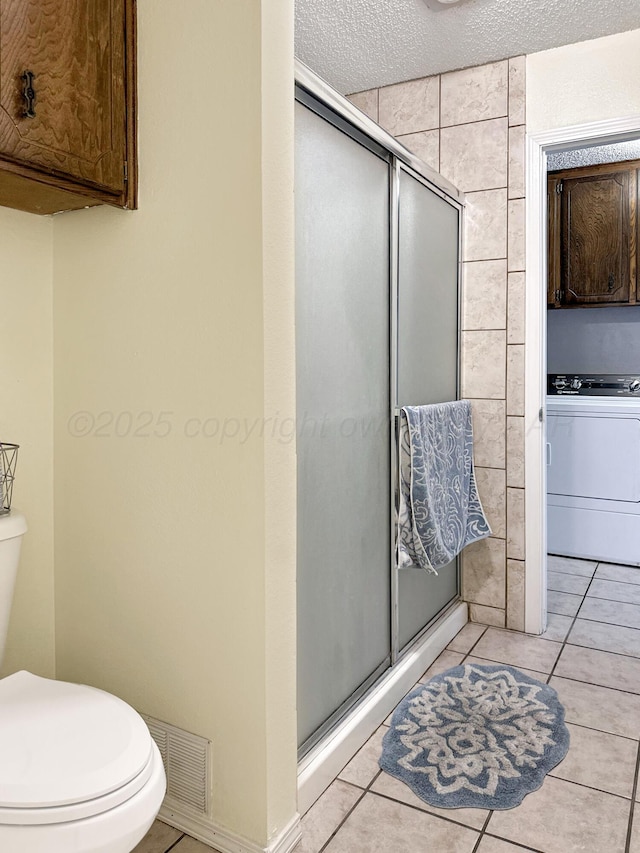 1620 Takewell St, Borger, TX 79007 - bathroom featuring washer / clothes dryer, a shower stall, toilet, a textured ceiling, and tile patterned floors