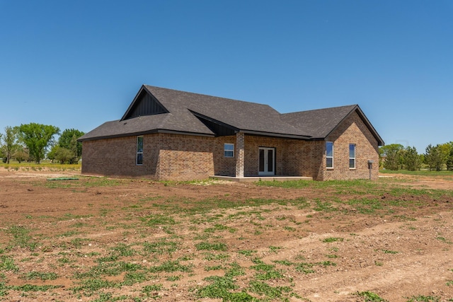 30 Country Club Dr, Farwell, TX 79325 - view of side of home with a shingled roof, board and batten siding, brick siding, and french doors