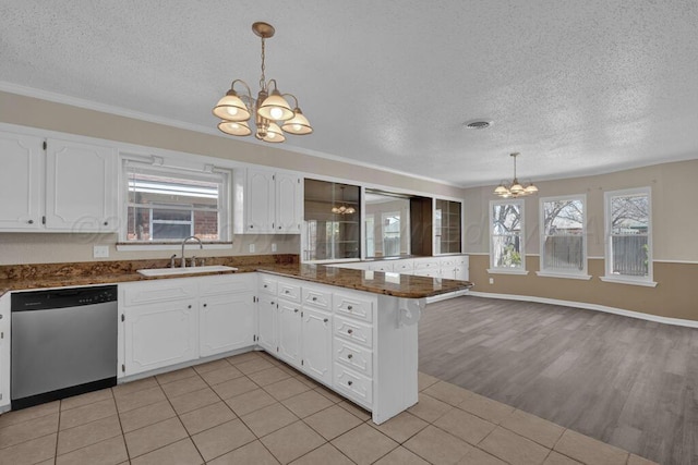 kitchen with an inviting chandelier, a sink, a peninsula, a textured ceiling, and stainless steel dishwasher