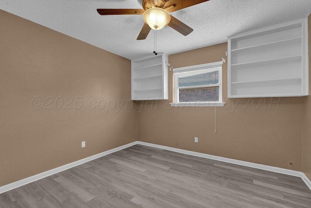 empty room featuring baseboards, a textured ceiling, wood finished floors, and ceiling fan