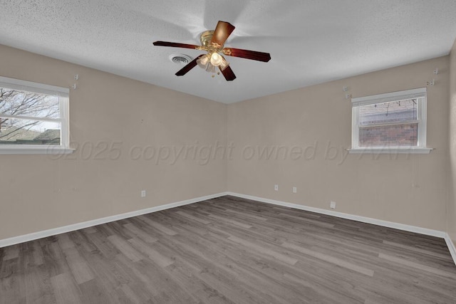 spare room with plenty of natural light, a textured ceiling, a ceiling fan, and wood finished floors