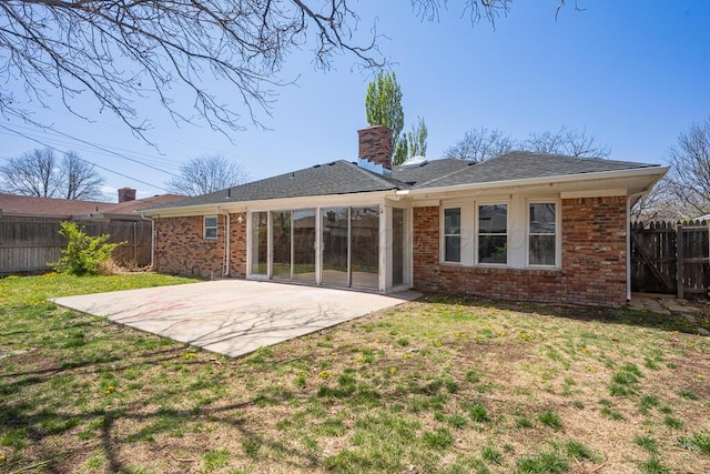 rear view of property featuring a patio area, brick siding, fence, and a lawn