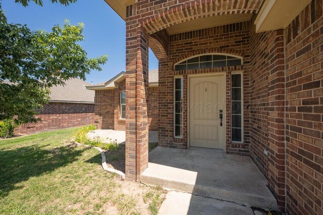 1800 Berkley Ct, Amarillo, TX 79118 - view of exterior entry with brick siding, a patio, and a yard