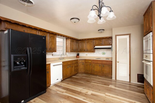 3607 Julie Dr, Amarillo, TX 79109 - kitchen with white appliances, under cabinet range hood, light countertops, brown cabinets, and a sink