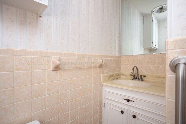3607 Julie Dr, Amarillo, TX 79109 - bathroom with wallpapered walls, vanity, tile walls, and wainscoting