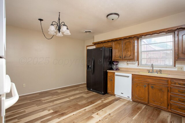 3607 Julie Dr, Amarillo, TX 79109 - kitchen with dishwasher, a sink, black fridge, a chandelier, and light wood finished floors