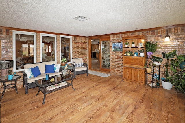 3508 Reeder Dr, Amarillo, TX 79121 - living area featuring brick wall, visible vents, a textured ceiling, and wood finished floors