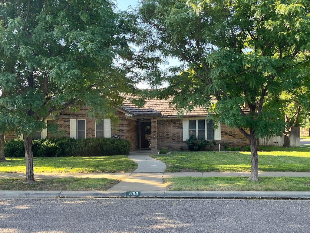 7100 Bayswater Rd, Amarillo, TX 79109 - obstructed view of property featuring brick siding, a tiled roof, and a front lawn