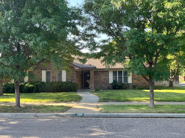 7100 Bayswater Rd, Amarillo, TX 79109 - obstructed view of property featuring brick siding, a tiled roof, and a front lawn
