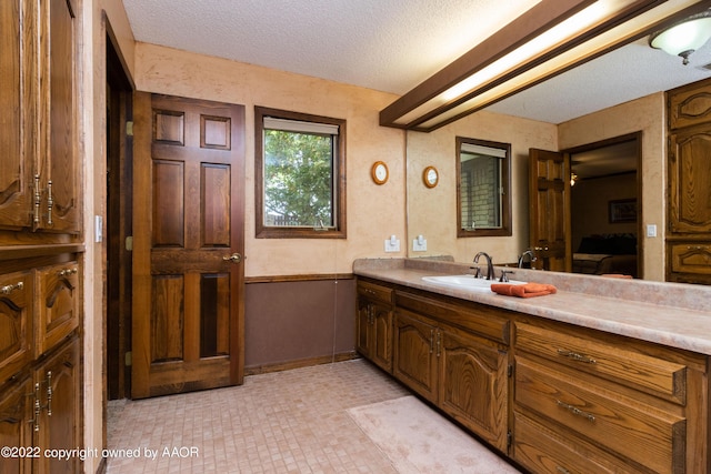 bathroom featuring vanity, wooden walls, and a textured ceiling