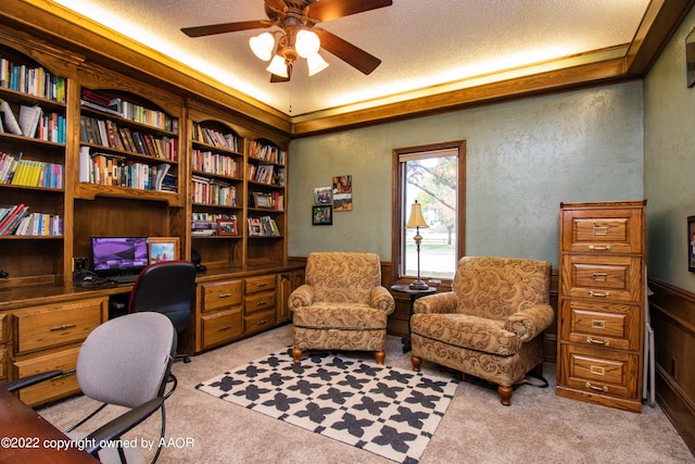 office area with built in desk, light carpet, ceiling fan, and a textured ceiling