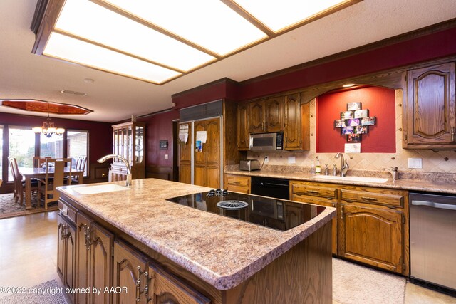 kitchen with sink, decorative backsplash, black appliances, and a center island with sink