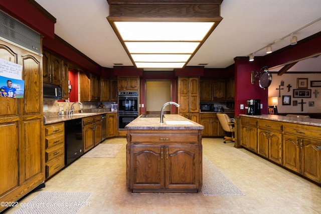 kitchen with built in desk, sink, a center island with sink, and black appliances