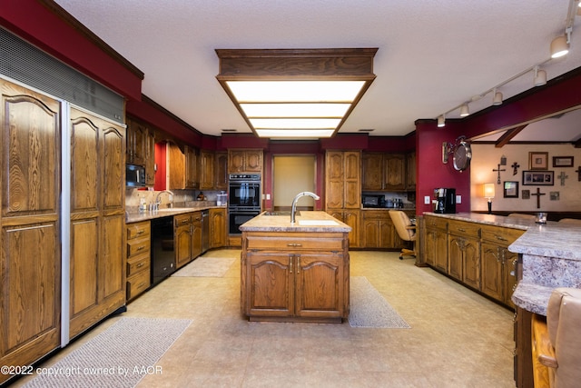 kitchen with sink, black appliances, built in desk, a center island with sink, and backsplash