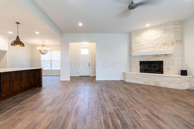8303 City View Dr, Amarillo, TX 79118 - unfurnished living room featuring a ceiling fan, wood finished floors, a stone fireplace, baseboards, and a chandelier