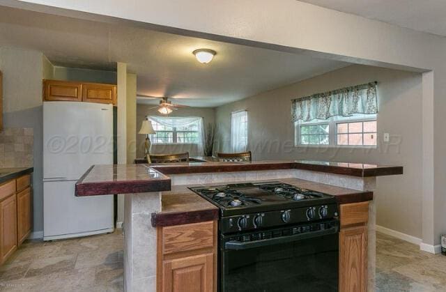 kitchen with ceiling fan, white fridge, and black gas stove