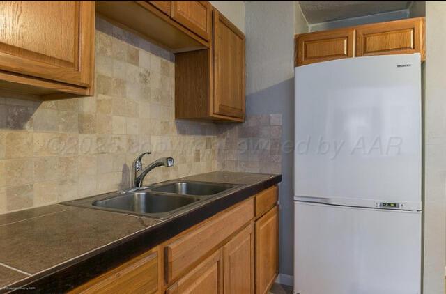 kitchen with sink, white fridge, and backsplash