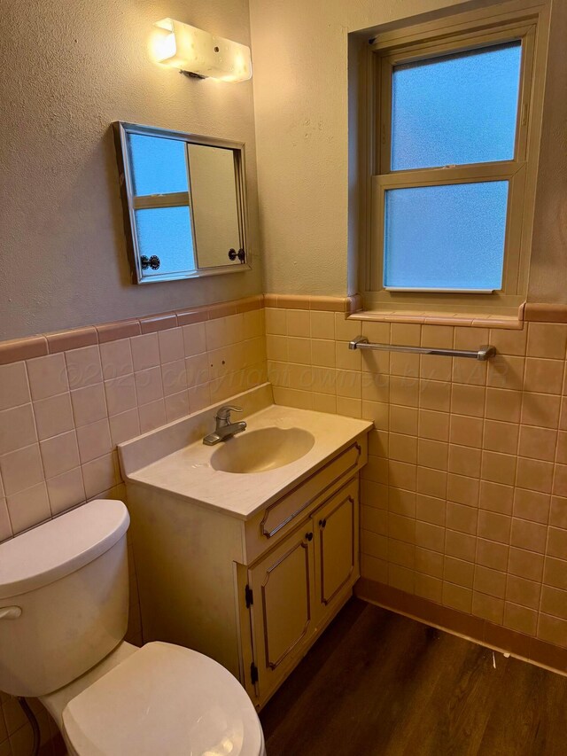 408 Jupiter St, Pampa, TX 79065 - half bath with tile walls, toilet, vanity, wainscoting, and wood finished floors