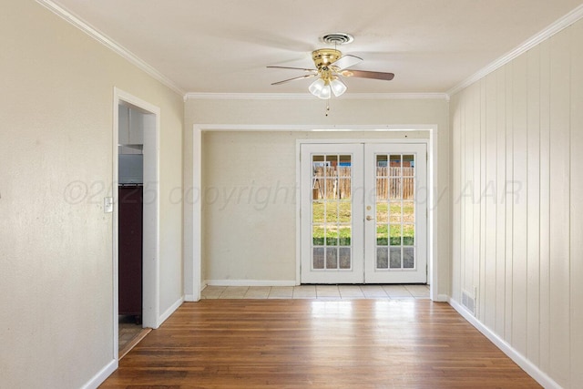 unfurnished room with french doors, wood finished floors, ceiling fan, ornamental molding, and baseboards