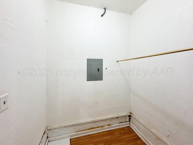 clothes washing area with electric panel and wood finished floors