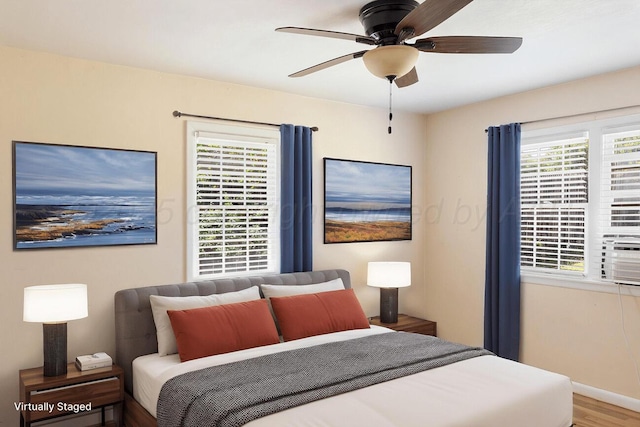 bedroom with multiple windows, baseboards, wood finished floors, and ceiling fan