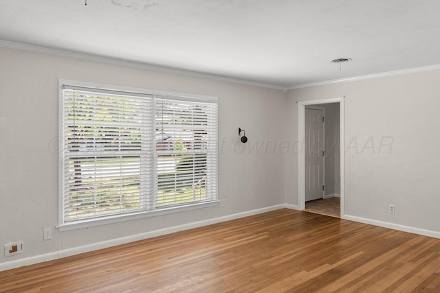 unfurnished room with healthy amount of natural light, wood finished floors, ornamental molding, and baseboards
