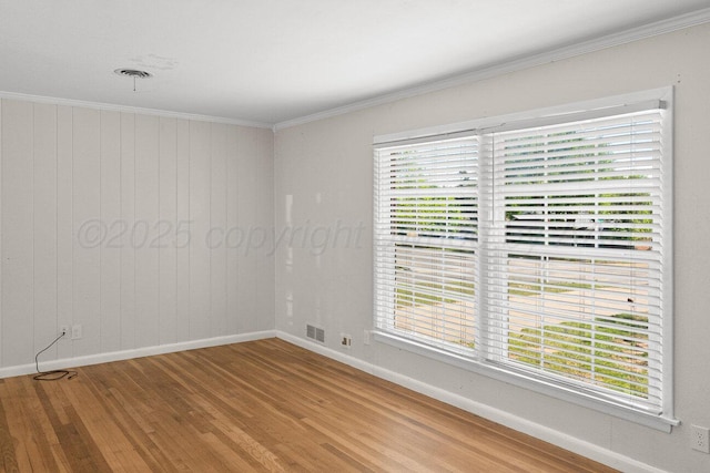 unfurnished room featuring wood finished floors, baseboards, and crown molding