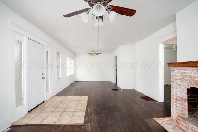 unfurnished living room featuring ceiling fan, wood-type flooring, and a fireplace