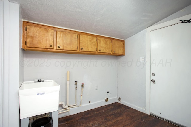 clothes washing area featuring dark wood-type flooring, cabinets, sink, and a textured ceiling