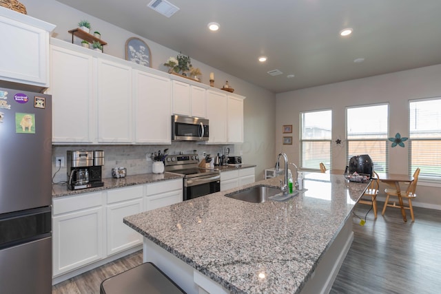 1839 Montaluse Rd, Amarillo, TX 79118 - kitchen with stainless steel appliances, wood finished floors, white cabinets, a center island with sink, and recessed lighting