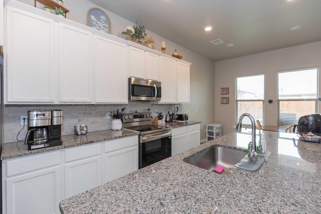 1839 Montaluse Rd, Amarillo, TX 79118 - kitchen featuring appliances with stainless steel finishes, backsplash, white cabinetry, recessed lighting, and light stone counters