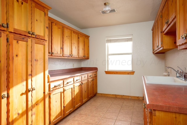 kitchen with light tile patterned floors, a textured ceiling, and sink