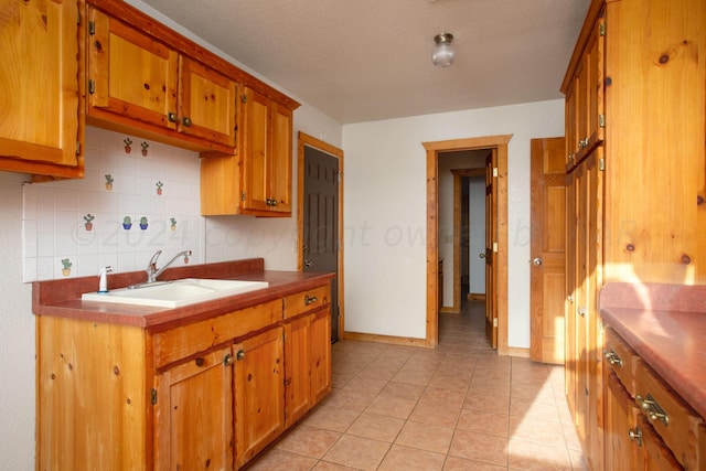 kitchen with light tile patterned flooring, a textured ceiling, sink, and decorative backsplash