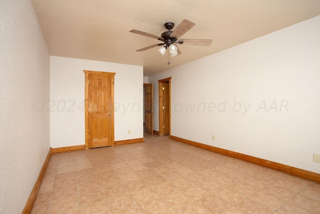 empty room with ceiling fan and a textured ceiling