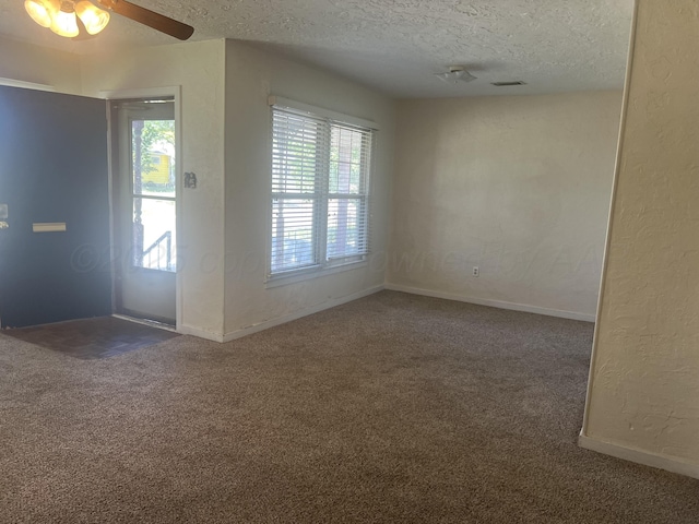 interior space featuring ceiling fan, dark carpet, and a textured ceiling