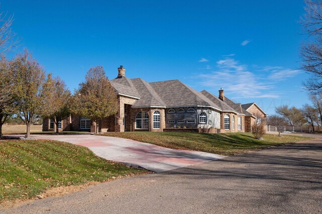 121 Quail Blvd, Amarillo, TX 79124 - french country inspired facade with a chimney, a front yard, concrete driveway, and brick siding