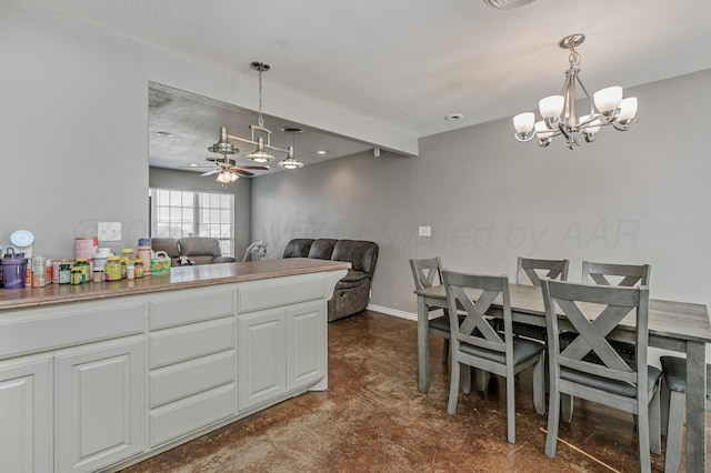 kitchen with ceiling fan with notable chandelier, open floor plan, white cabinetry, baseboards, and hanging light fixtures