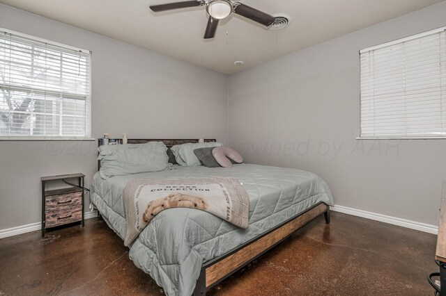 bedroom featuring a ceiling fan, concrete floors, and baseboards