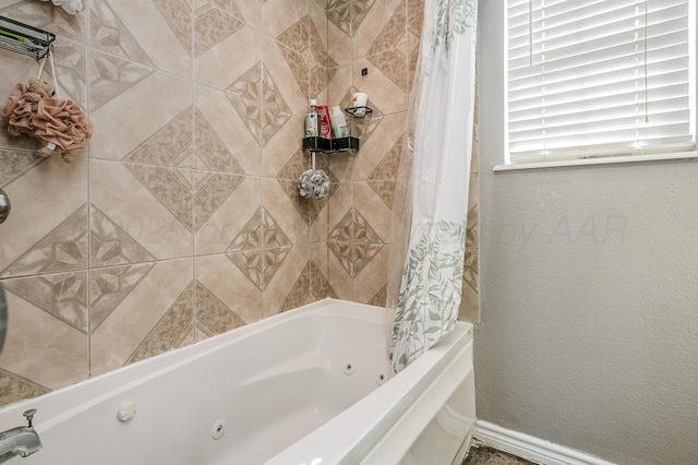 full bath with a combined bath / shower with jetted tub, baseboards, and a textured wall